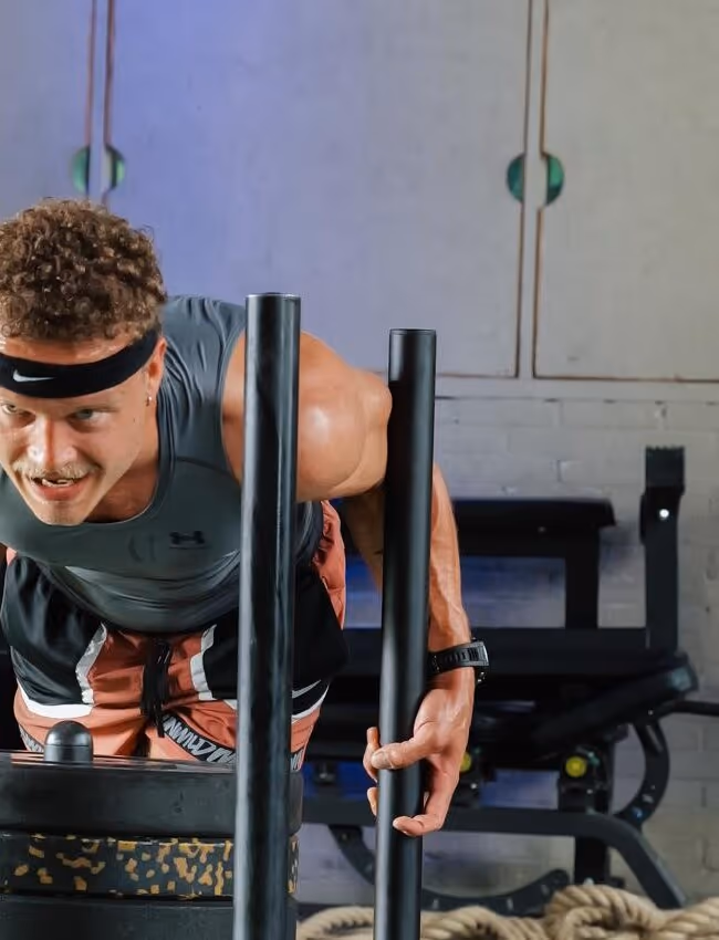 Sporter duwt een sled tijdens een High Performance training bij Gustafit in Groningen